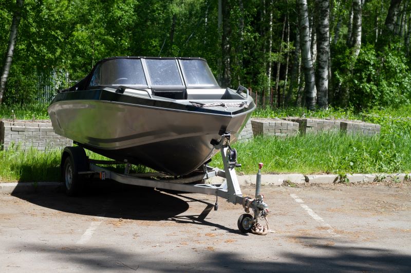 A boat on a trailer in a parking lot awaiting boat trailer repair.