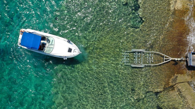 A boat and a trailer in the water. Possibly in need of boat trailer repair due to water. 