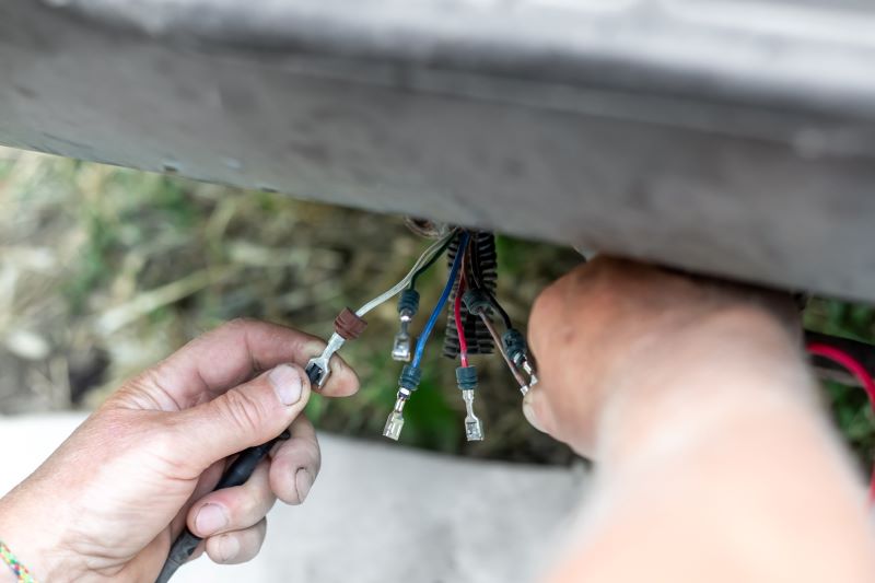 A man holds in his hands wires with terminals for connecting rear brake lights to a car.